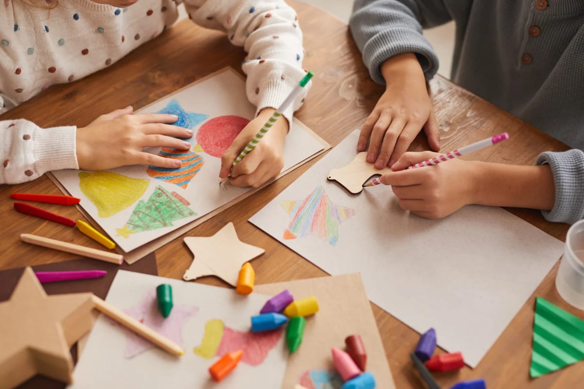 Children drawing together with crayons at a shared table